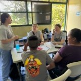 A group of Norwich University School of Nursing students sitting around a table in a screened room with trees outside