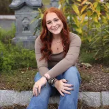 A woman smiles in a portrait taken in a garden.