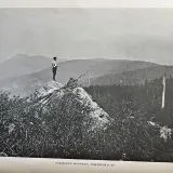 A person stands on a rocky ledge above Partridge Mountain in Northfield, Vermont.