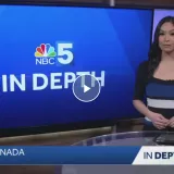 TV news anchor stands beside an NBC5 In Depth screen in a studio.