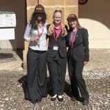 Three students wearing ROOK hats and conference badges stand in front of a stone column outdoors.