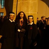 Student poses with two nuns outside a stone building at night.