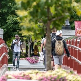 Norwich University students walking across the alumni bridge on campus.