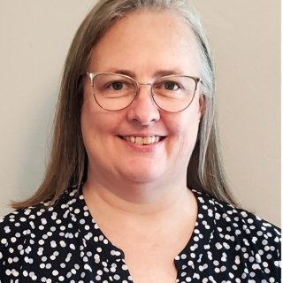headshot of woman with glasses and a print blouse