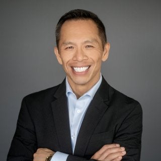 Hansen in suitcoat and blue shirt with arms crossed