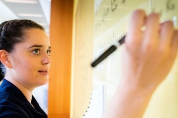Norwich Mathematics Student Writing Complex Formulas on Whiteboard