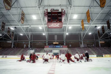 Norwich University women’s ice hockey team kneels at center ice during practice at Kreitzberg Arena before traveling to the NCAA Frozen Four