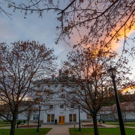 Kreitzberg Library stands behind leafless trees under a colorful evening sky