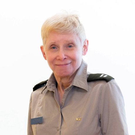 Person with blond cropped hair in uniform.