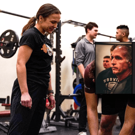 Strength coach watches a weightlifting session in a gym with several people and exercise equipment.