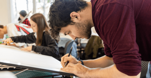 Norwich architecture student designing on a drafting table.