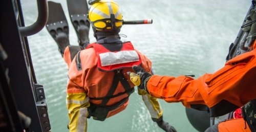 Coast Guard trainee jumping from a helicopter into the water.