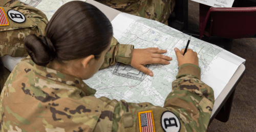 Army ROTC student working on a map in classroom.