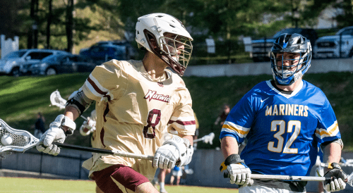 Two lacrosse players, one in a cream jersey with number 8, another in a blue jersey with number 32, on field.
