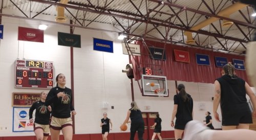 Women's basketball players warming up in a gym before a game.