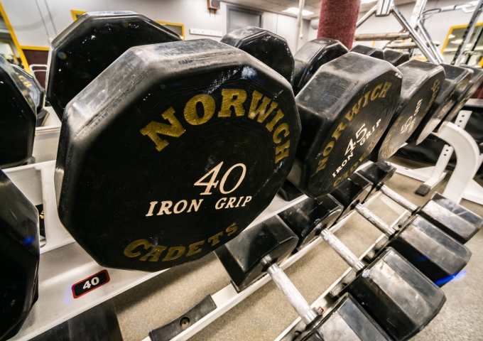 Norwich Iron Grip 40-pound dumbbell rests on a weight rack at a gym, displaying yellow lettering on its black surface.