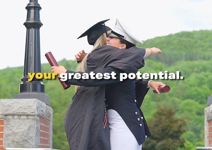 Civilian and corps students hugging in graduation attire.