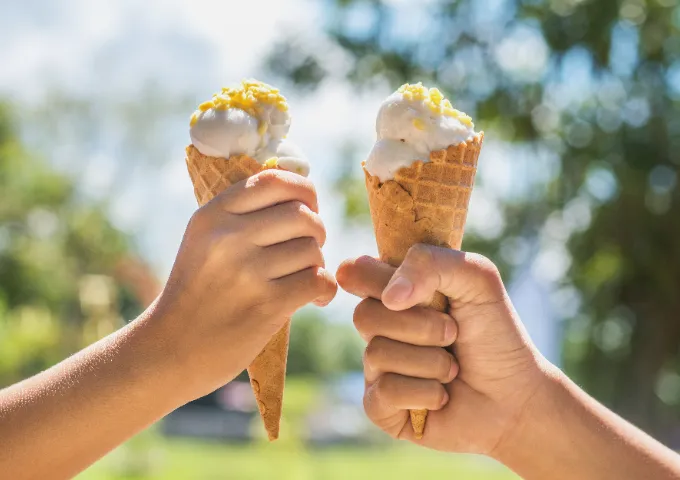 Two hands holding ice cream cones.