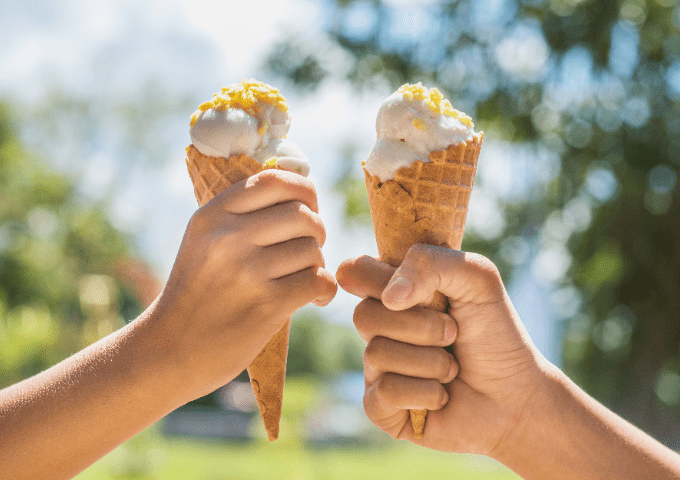 Two hands holding ice cream cones.