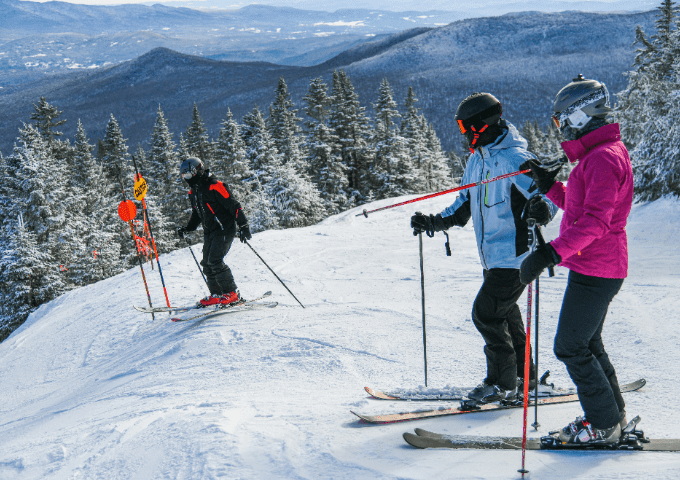Skiers at the top of the ski mountain with a view of the mountains.