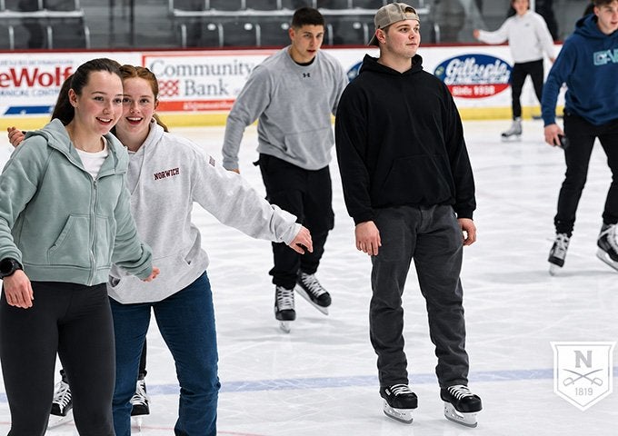Norwich students ice skating together at an indoor rink.