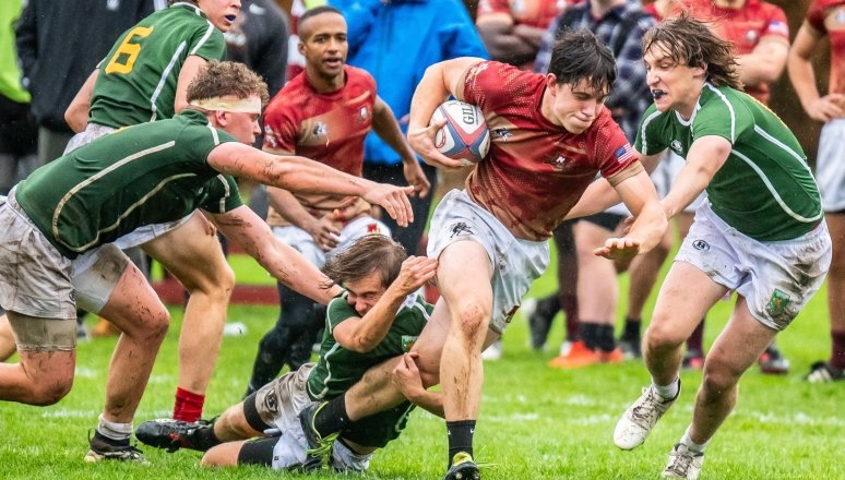 Norwich Men's Rugby player mid-run as he avoids being tackled by opposing team.