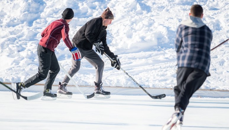 Norwich University students playing ice hockey on campus rink.
