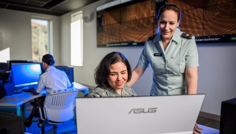 Norwich cadet working on a computer with help from a faculty member.