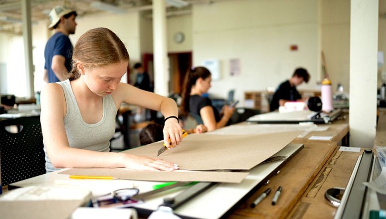 Architecture student working on project inside the studio with other students around her.