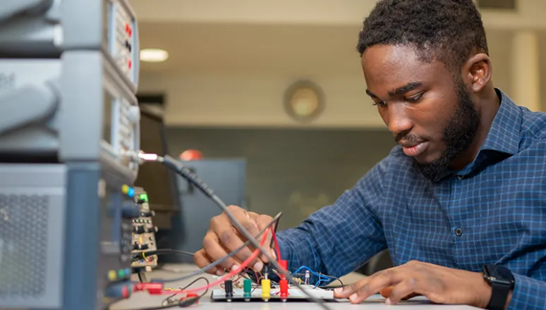 Male student working on a tech hardware in class.