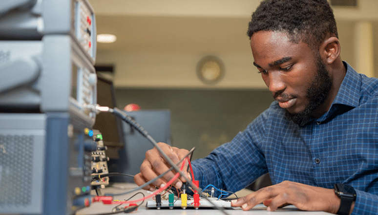 Male student working on a tech hardware in class.