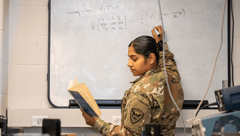 Corps student Vibho working on a math problem on a white board.
