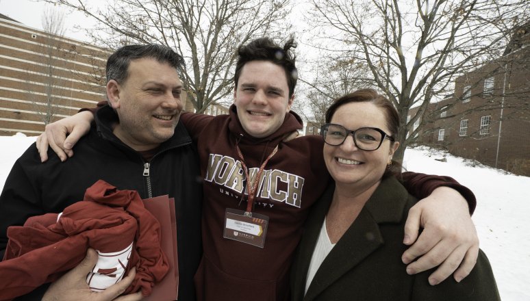 Student with parents visiting campus on a snowy day.