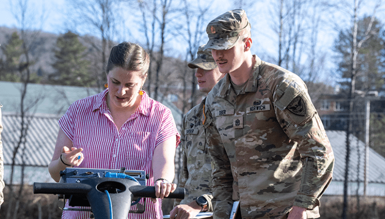 Faculty and students in Geology class reviewing data readings outdoors using high-tech equipment.