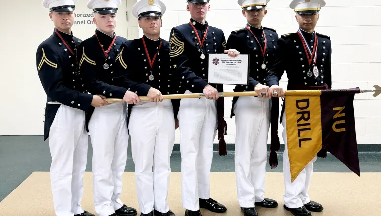 Group of six Norwich University cadets in uniform, holding a ceremonial banner and an award plaque.