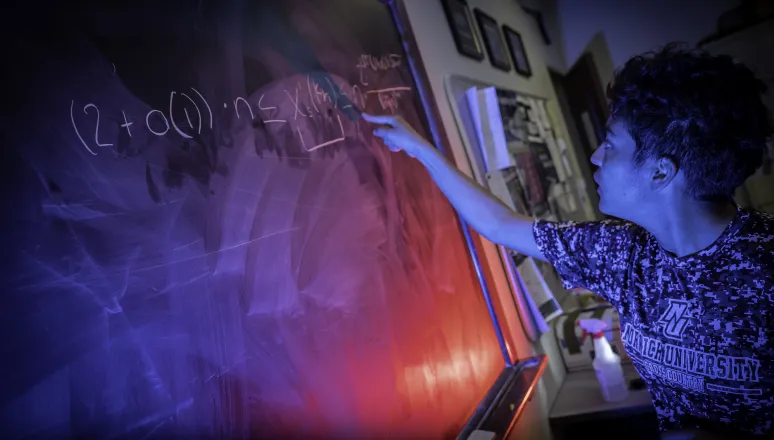 Student writing problem on chalkboard