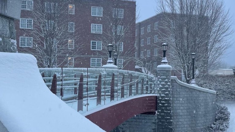 Snowy campus photo of the Alumni Bridge looking toward the barracks.