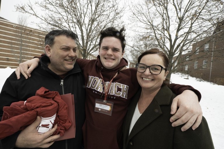 Student with parents visiting campus on a snowy day.