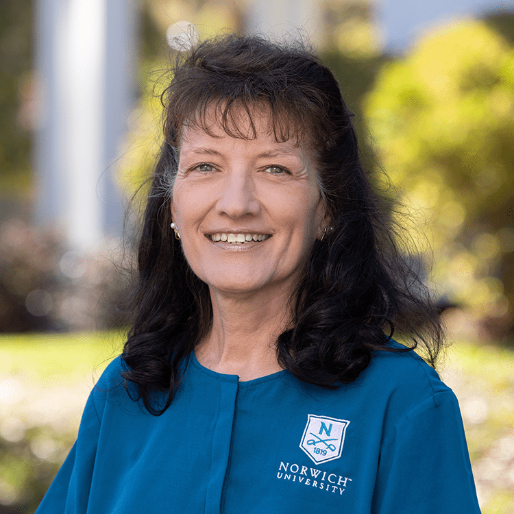 A portrait of Robin smiling outside.