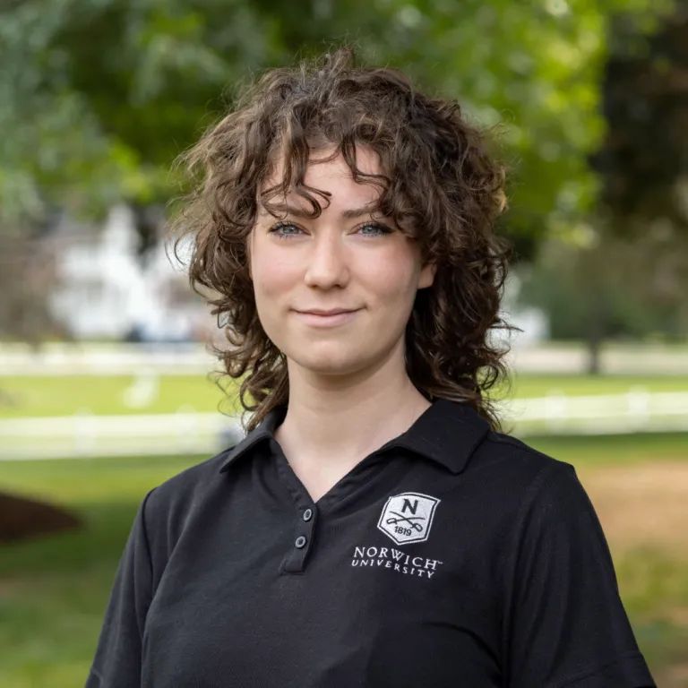 Portrait photo of Emma outside wearing a black Norwich polo.