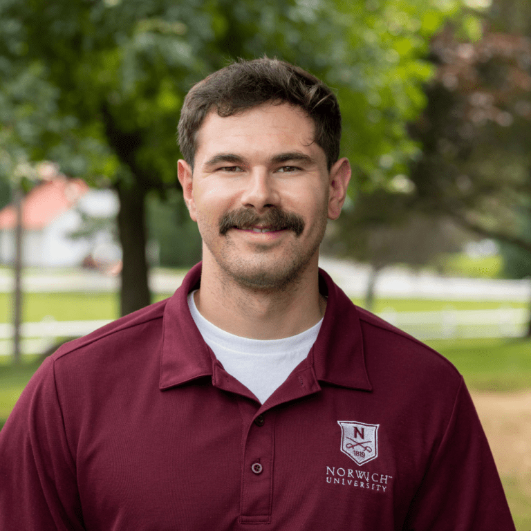Portrait of Dennis Pollicino outside wearing a maroon Norwich polo.