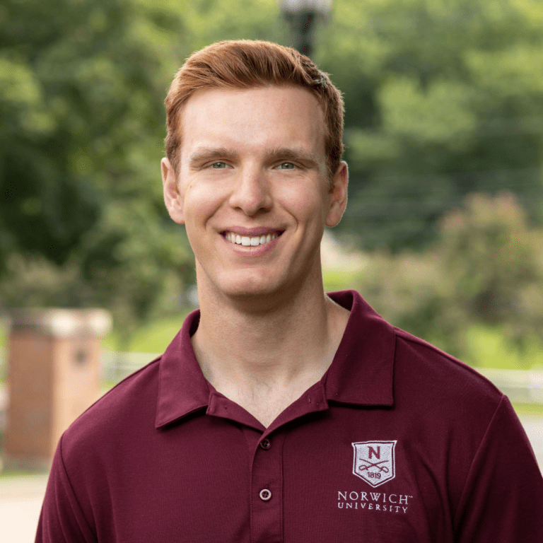 Portrait of Glen Sauter, Admissions Counselor on campus with trees behind him and wearing a maroon Norwich polo.