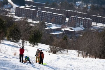 Sledding Party at Shaw Outdoor Center with Norwich Campus in background