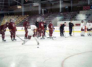 Norwich University women’s ice hockey player takes a shot during practice while teammates and coaches watch at Kreitzberg Arena ahead of NCAA Frozen Four