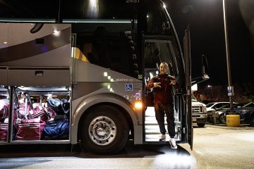 Norwich University women’s ice hockey head coach Justin Simpson steps off team bus at night upon arrival.