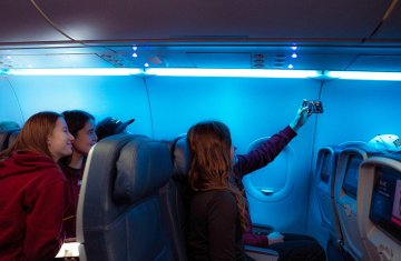 Norwich women’s hockey players sit together on airplane taking photo during flight to NCAA Frozen Four 