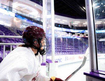 Norwich women’s hockey player in helmet heading onto ice at Anderson Arena