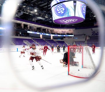 Norwich goalie makes a save on close shot during practice while teammate shoots toward net 