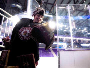 Norwich women’s hockey goalie in full gear looks toward camera while walking off ice from practice
