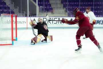 Norwich goalie makes a save on close shot during practice while teammate shoots toward net 